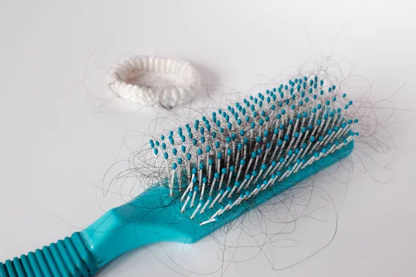 Hair fall out. Hairbrush with hair on a white background. Comb in hand.