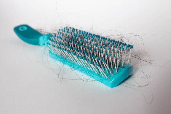 Hair fall out. Hairbrush with hair on a white background. Comb in hand. — Stock Photo, Image