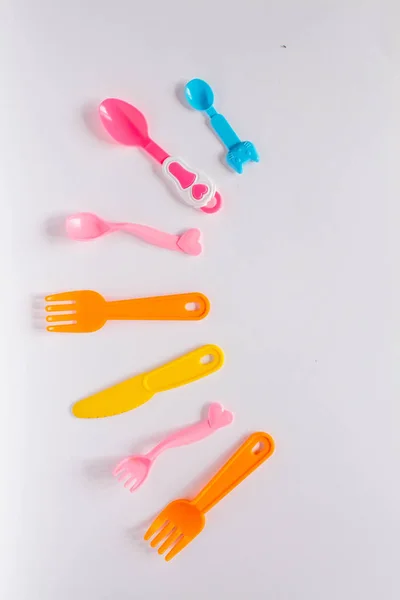 Children plastic dishes on a white background, forks, spoons, plate with space for text. Flat lay, top view minimal concept. — Stock Photo, Image