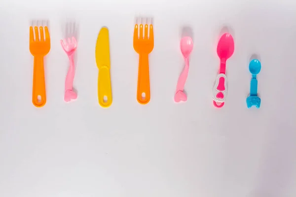 Pratos de plástico de crianças em um fundo branco, garfos, colheres, prato com espaço para texto. Flat lay, vista superior conceito mínimo . — Fotografia de Stock