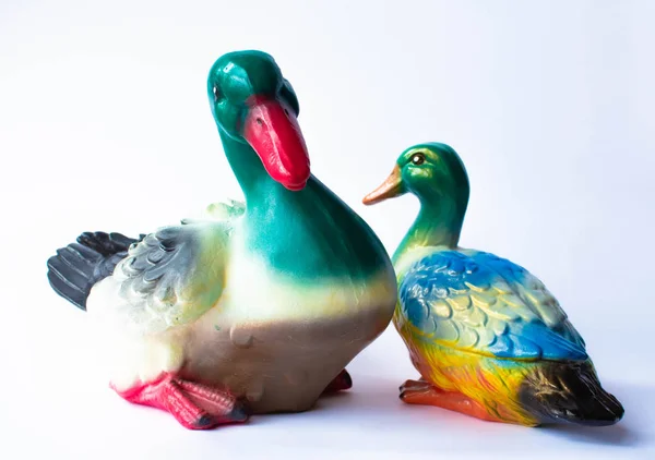 Ceramic statuette of a duck on a white background with brightly colored feathers. Duckling with mother duck