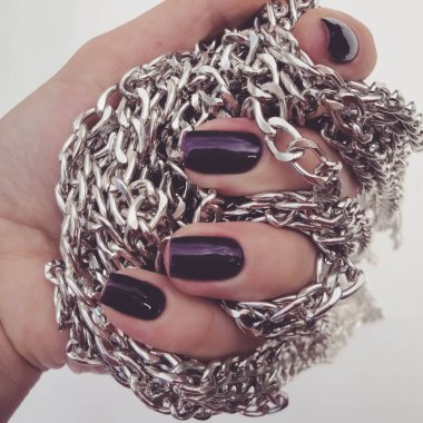 Güzel kırmızı tırnaklar ve zinciri kapatın. Güzel, bakımlı mor oje ve zinciri ile elinde çivi