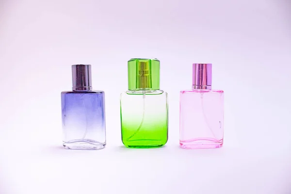 Glass bottle of perfume on white background. Pink, blue, green, black bottle. Women's and men's perfume. Aromatherapy, spa. — Stock Photo, Image