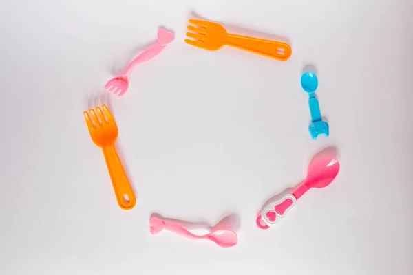 Muitos garfos plásicos coloridos, colheres e facas no fundo branco com espaço de cópia, vista superior. Dispositivos para alimentos para bebés — Fotografia de Stock