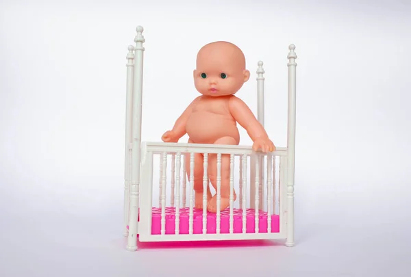 toy baby in the crib. White nursery for young children. Little boy learning to stand in his crib. child playing in sunny bedroom.