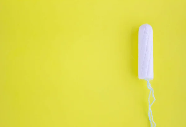 One swab with cotton on a yellow background. The concept of the period of the menstrual cycle. Top view, flat lay. — Stock Photo, Image