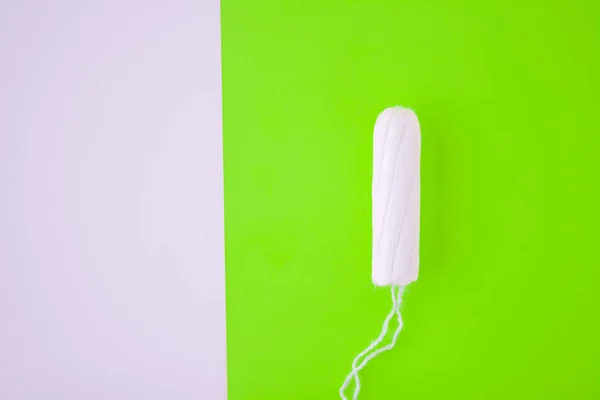 O conceito do ciclo menstrual, menstruação e produtos íntimos com um cotonete interno, em fundo verde com espaço de cópia — Fotografia de Stock