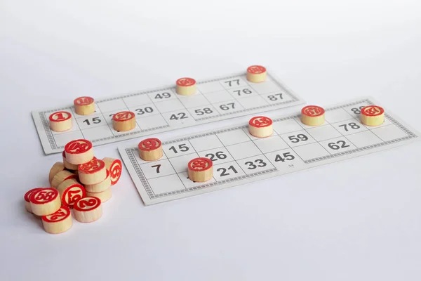 Bingo o juego de lotería. barriles de madera de lotería en las tarjetas. Tarjetas y fichas para jugar bingo en una mesa blanca — Foto de Stock