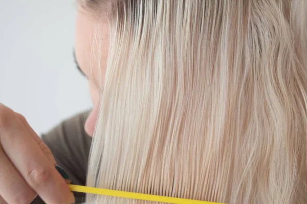 Uma jovem está a tentar pentear o cabelo. Pente de cabelo branqueado quebradiço pente — Fotografia de Stock