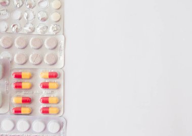 Solda solda zatürree için renkli haplar ve kapsüller bulunan beyaz yüzey. Model yap. Düz konum.