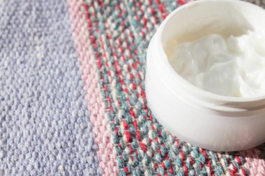 Çok renkli arka planda cam bir güzellik kremi kavanozu. Cilt kozmetik, kaplıca ve sağlık merkezi kavramı, yüz bakımı..