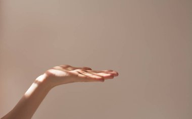  Kadın eli kopyalama alanını ve beyaz arka planda güzel gölgeleri olan bir nesneyi tutuyor. Güneşin düzeni ve çerçevesi.