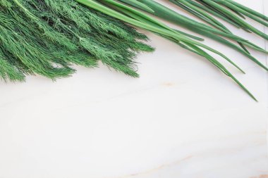Beyaz bir masada taze dereotu ve sebze bahçeli soğan. Metin için kopyalama alanı olan kart. Üst Manzara. Düz yatıyordu.