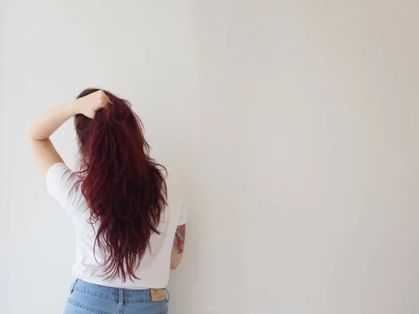 Brunette with long hair stands with his back to the camera, hair is bright color, slim figure concept health and beauty.