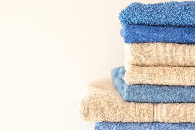 Mavi ve bej renkli banyolar temiz terry havlular beyaz arka planda fotokopi alanı ile yakın plan. Sauna için temiz havlular..