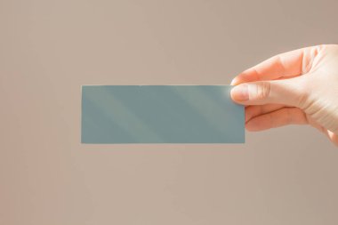 Kadın eliyle boş bir sayfa, yazı ve tasarım için mavi kart. Poster maketi, eller ve çerçeveler.