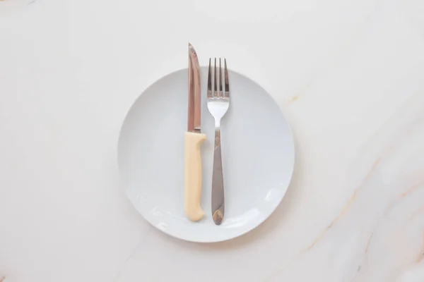 Placa branca vazia com talheres em uma mesa de mármore, pires, garfo e faca. O conceito de dieta, jejum — Fotografia de Stock