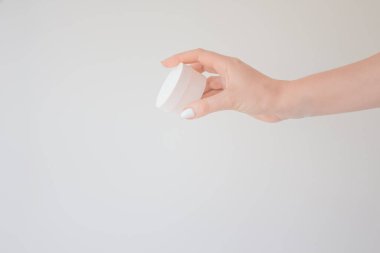 Krem ya da kadın elinde losyon için yuvarlak bir kaplama. Cilt bakımı ve güzellik konsepti. Mockup, beyaz arkaplanda boşluk kopyala