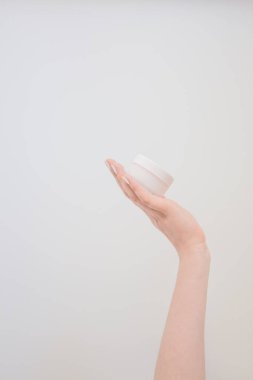 Krem ya da kadın elinde losyon için yuvarlak bir kaplama. Cilt bakımı ve güzellik konsepti. Mockup, beyaz arkaplanda boşluk kopyala.