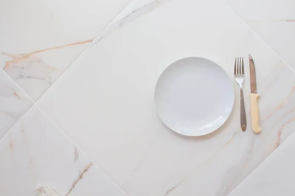 Placa branca vazia com talheres em uma mesa de mármore, pires, garfo e faca. O conceito de dieta, jejum — Fotografia de Stock