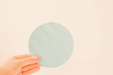 Yuvarlak mavi kart ve elinde fotokopi alanı olan genç bir kadın. Pastel mavisi kartpostal düzeni. İndirim, açılış, yeni ürün ve avantajlı bir teklif hakkında bilgilendirme amaçlı yuvarlak tabak.