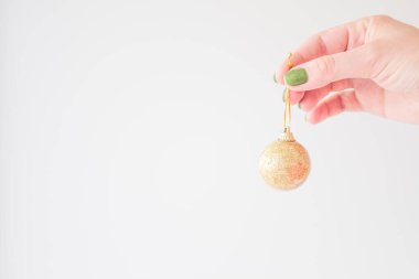  Genç bir kadının elindeki altın noel balosu şık minimalist tasarımın için beyaz bir arka planla alay ediyor..
