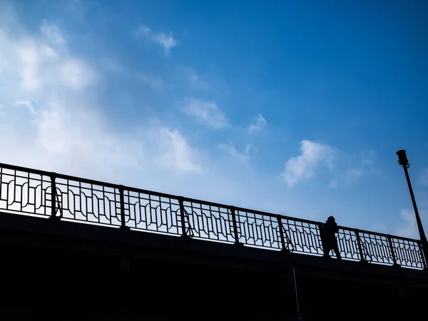 Silhueta Homem Caminhando Ponte Com Uma Cerca Visível Poste Claro — Fotografia de Stock