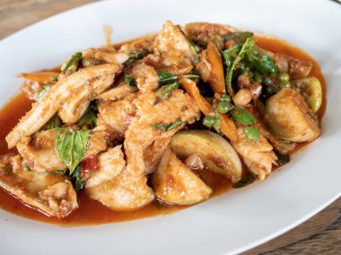 Tay sıcak ve baharatlı balık yerel malzemeler ile tavada kızartılmış; kırmızı biber macun, pepercorn, fesleğen yaprağı ve patlıcan, beyaz plaka üzerinde.