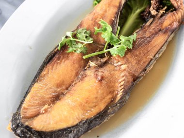 Derin yağda kızartılmış Kral Uskumru kişniş dal ile serpilir.