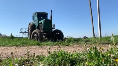 Mavi traktör kaldırılmış harrow sürücüsü yeşil alana geri dönüyor.