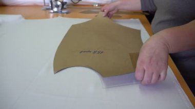 Profesyonel terzi elleri kumaştan kağıt şablonu alır