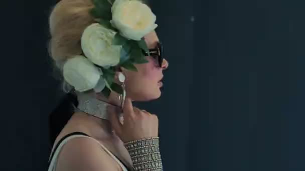 Modelo elegante en gafas negras y rosas blancas en la cabeza posa — Vídeos de Stock