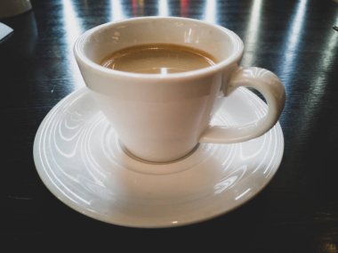 Koyu masada bir fincan kahve.