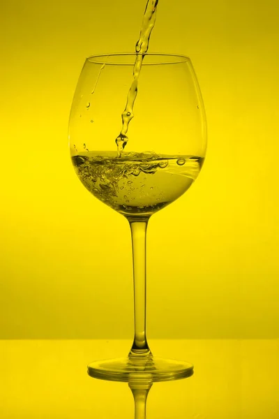 Enchendo Copo Derramando Vinho Sobre Fundo Amarelo — Fotografia de Stock