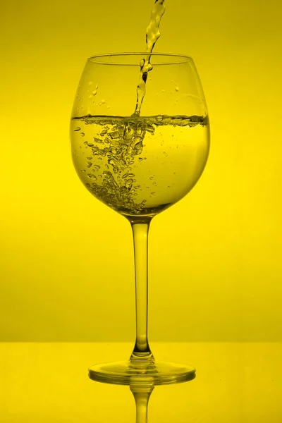 グラスを充填し 黄色の背景にワイングラスを注ぐ — ストック写真