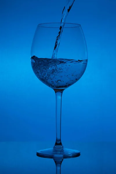 Enchendo Copo Derramando Vinho Fundo Azul — Fotografia de Stock