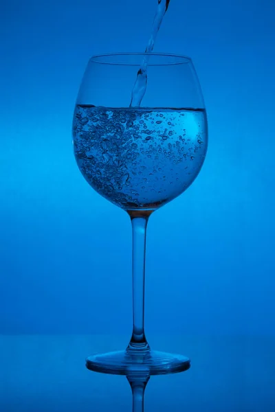 Γεμίζοντας Γυαλί Χύνοντας Χρώμα Του Κρασιού Μπλε Φόντο — Φωτογραφία Αρχείου