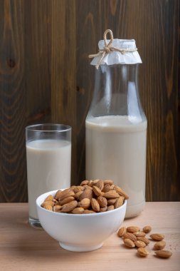 Ahşap arka planda cam badem sütü ve organik badem, Alternatif Süt