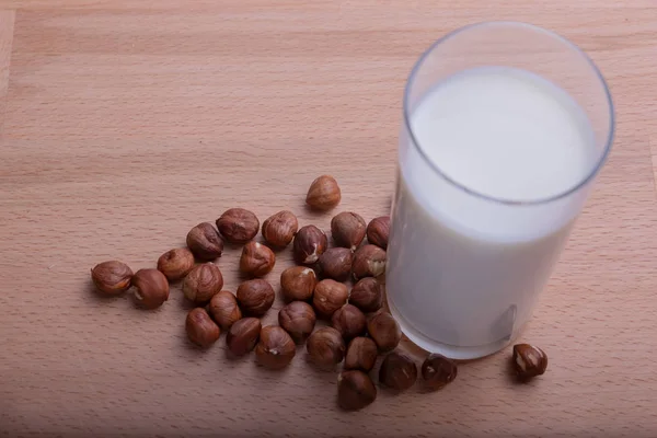 Ореховое молоко в стекле и органические лесные орехи на деревянном фоне, Альтернативное молоко — стоковое фото