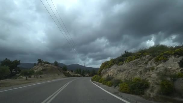 Blick aus dem Auto, Waldstraße in den Bergen mit Blick auf den dramatischen Himmel — Stockvideo