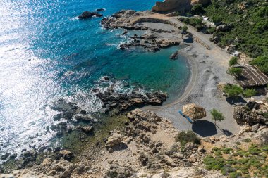 Çakıl plajında şezlong ve şemsiye.