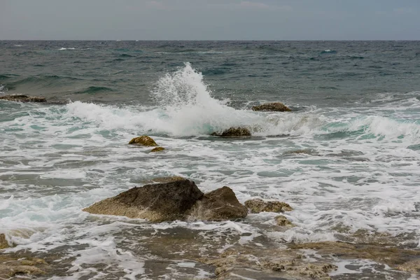 Fale rozprysków i wiatr na plaży kamienia morskiego z dramatyczne niebo — Zdjęcie stockowe