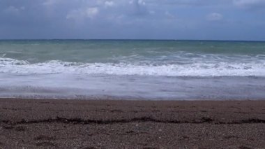 bulutlu gökyüzü, rüzgar ve dalgalar kumlu bir deniz plajında