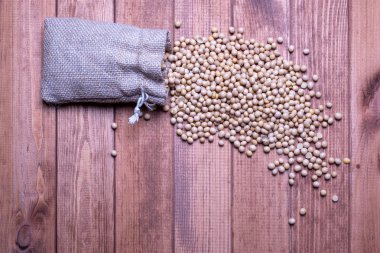 Soya fasulyesi ahşap bir masanın üzerinde açık bir tuval çanta düşmek. Soya b