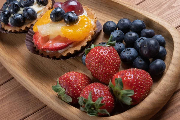 Tartaletas de frutas en un plato de madera en la mesa, cáscara horneada fruta — Foto de Stock