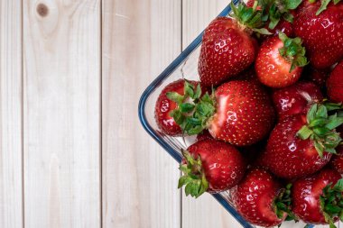 açık ahşap masada çilek ile kare cam kase