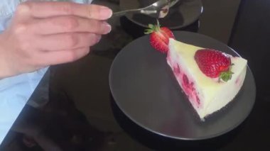 kız siyah cam masada krem meyveli kek, kek ve bir fincan siyah kahve yiyor