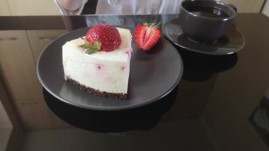 kız siyah cam masada krem meyveli kek, kek ve bir fincan siyah kahve yiyor