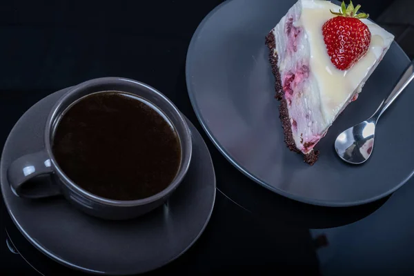 Pastel de fruta crema y una taza de café negro en una mesa de vidrio negro —  Fotos de Stock