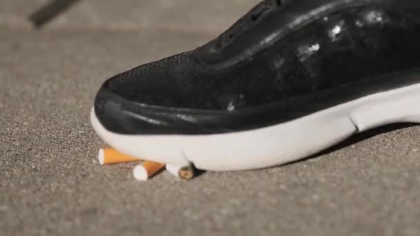 女性がアスファルトでタバコを踏みつけ タバコをやめ 喫煙をやめる — ストック動画